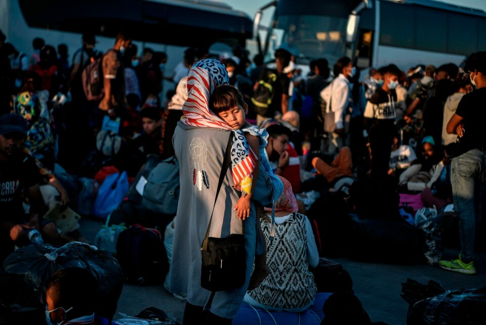 Regjeringa har sagt den skal hente 50 flyktninger fra den ødelagte Moria-leiren i Hellas. Greske myndigheter har nå begynt å flytte migranter og flyktninger fra de overfylte leirene på de greske øyene til fastlandet. Foto: Louisa Gouliamaki / AFP / NTB A woman holds her child as refugees from the islands of Lesbos, Chios, Samos , Kos and Leros wait to board buses after disembarking at the port of Lavrio, some 70 km south-east of Athens, prior to be transferred to camps in mainland Greece, on September 29, 2020. - The first groups of 724 refugees from the gutted Moria camp and another 210 from the camps at other Aegean islands were transferred on September 29, 2020, in a bid to decongest the overcrowded island camps. (Photo by LOUISA GOULIAMAKI / AFP)
