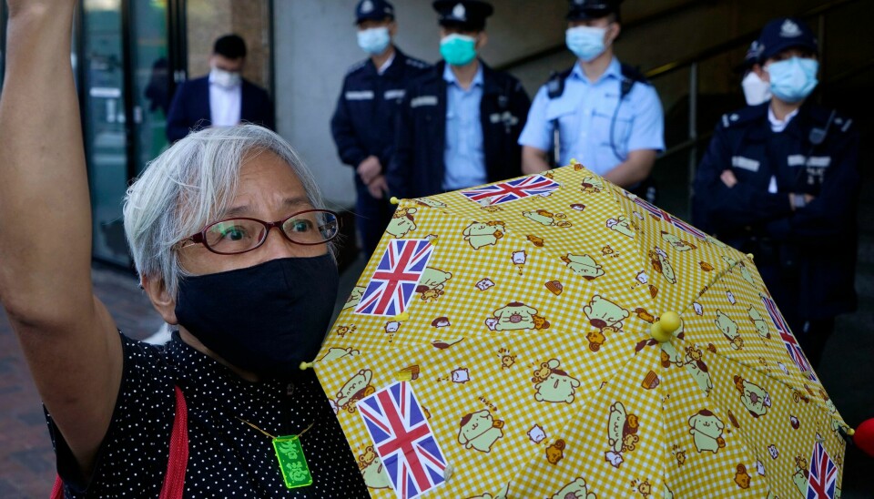 Demokratiaktivist Alexandra Wong med sin karakteristiske gule paraply under en protest utenfor kontoret til kinesiske myndigheter i Hong Kong under en protest i desember 2020. Pro-democracy activist Alexandra Wong holding yellow umbrella with British flags protests outside the Chinese central government's liaison office, in Hong Kong, Monday, Dec. 28, 2020, to demand the release of the 12 Hong Kong activists detained at sea by Chinese authorities. (AP Photo/Kin Cheung)