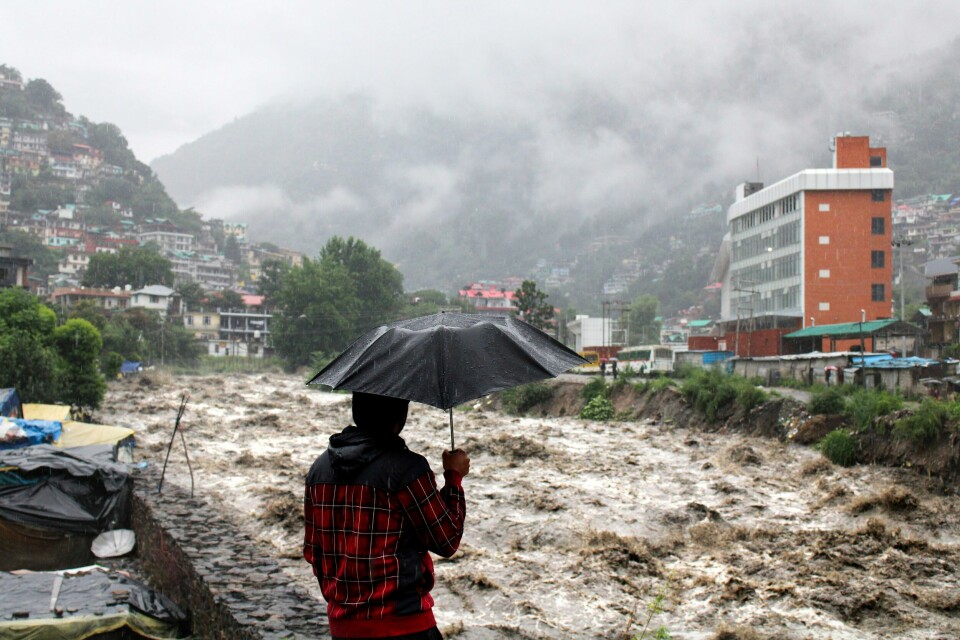 En mann ser ut over den oversvømte elva Beas i byen Kullu i Himachal Pradesh søndag ettermiddag. Uværet i delstaten har ødelagt flere hus og ført til jordskred og oversvømmelser som har tatt livet av flere mennesker. En mann ser ut over den oversvømte elva Beas i byen Kullu i Himachal Pradesh søndag ettermiddag. Uværet i delstaten har ødelagt flere hus og ført til jordskred og oversvømmelser som har tatt livet av flere mennesker. Foto: Aqil Khan / AP / NTB