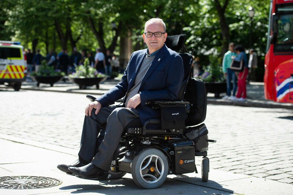 Lars Ødegård Mann med dress, sitter i elektrisk rullestol, med briller og smiler