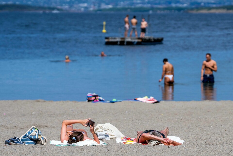 Folk koser seg i solen på Ingierstrand Bad ved Oslo mandag 14. juli. Folk koser seg i solen på Ingierstrand Bad i Oslo mandag denne uken. Tirsdag var det over 28 grader i Oslo, og varmere skal det bli. Foto: Javad Parsa / NTB