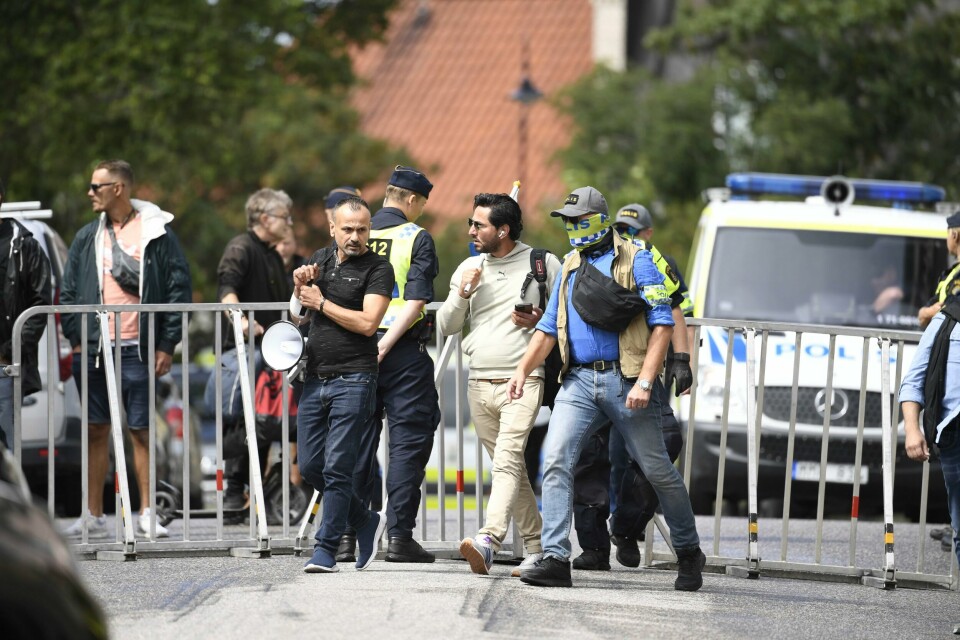 Den irakiske flyktningen Salwan Momika (i lyse klær) ble eskortert av politiet til et sted utenfor den irakiske ambassaden i Stockholm der han hadde tillatelse til å brenne et eksemplar av Koranen og det irakiske flagget 20. juli. Den irakiske flyktningen Salwan Momika (i lyse klær) ble eskortert av politiet til et sted utenfor den irakiske ambassaden i Stockholm der han hadde tillatelse til å brenne et eksemplar av Koranen og det irakiske flagget 20. juli. Foto: Caisa Rasmussen/TT via AP / NTB