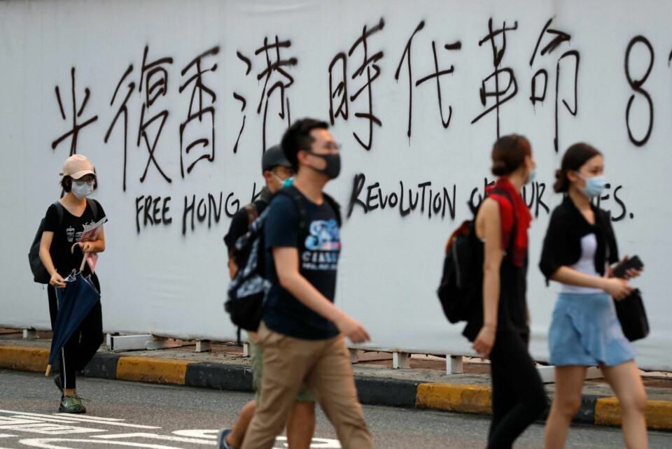 Demonstranter passerer en vegg med slagord i Hongkong.