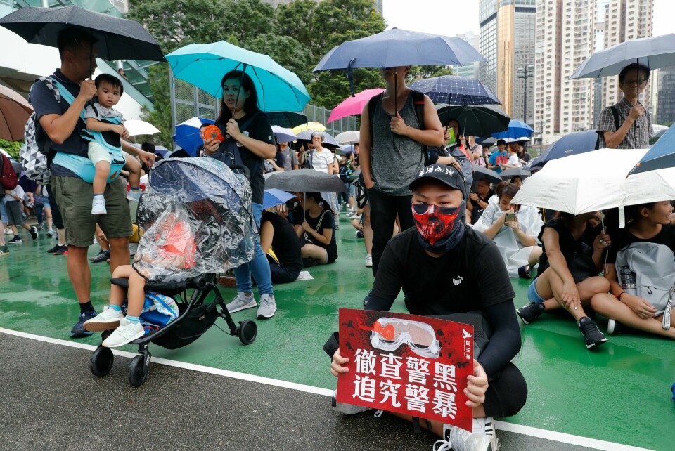 En av demonstrantene holder en plakat der det blir oppfordret til en grundig etterforskning av politivold og korrupsjon. A protester holds up a card which reads 'Thoroughly examine corrupt police, Investigate police brutality' during a rally in Hong Kong on Sunday, Aug. 18, 2019. A spokesman for China's ceremonial legislature condemned statements from U.S. lawmakers supportive of Hong Kong's pro-democracy movement, as more protests were planned Sunday following a day of dueling rallies that highlighted the political divide in the Chinese territory. (AP Photo/Vincent Thian)