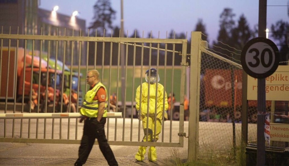 En person i fullt verneutstyr passer på ved den stengte porten inn til postterminalen i Stokke i Vestfold.