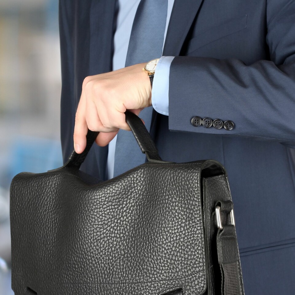 businessman holding leather briefcase checking time on his watch at the airport. businessman holding leather briefcase checking time on his watch at the airport.