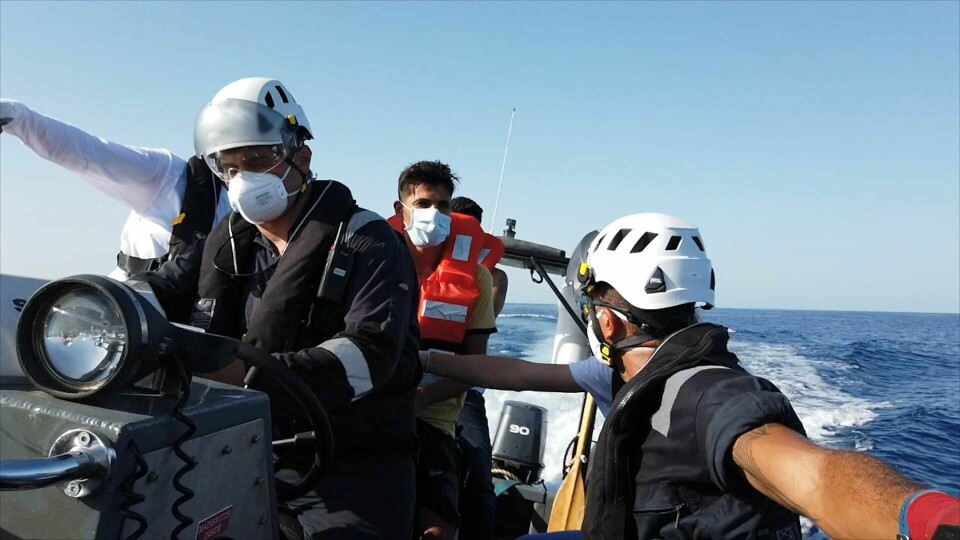 Redningsmannskaper snakker med en migrant som er reddet fra en gummibåt utenfor Libyas kyst 22. august i år.