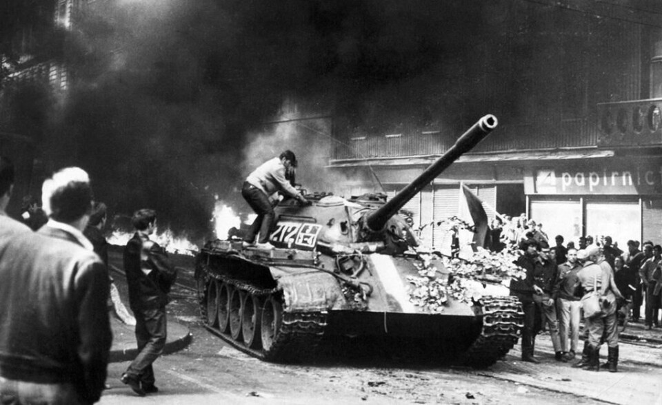 En ung mann tsjekker klatrer opp på en sovjetrussisk tanks i Vinohrady-gaten i Praha 21. august 1968. I bakgrunnen brenner påtente bildekk. TO GO WITH AFP STORY
(FILES) Picture taken on August 21, 1968 shows a young Prague resident climbing on a Soviet T-54 tank in the Vinohrady street near the state-owned radio building in Prague during confrontations between demonstrators and the Warsaw Pact troops and tanks, who invaded Czechoslovakia to crush the newfound freedom and re-establish a totalitarian regime. The Soviet occupation of Czechoslovakia 1968-1991 caused 402 deaths among the Czechs and Slovaks, according to a report by Czech historians in a 'Black Book of Soviet occupation' published on the occasion of 47th birthday invasion. AFP PHOTO / -