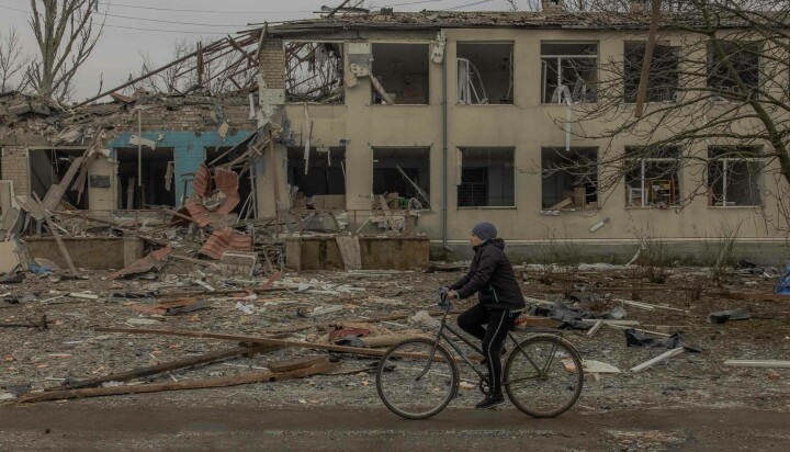 En kvinne sykler forbi et skolebygg som ble bombet i stykker i en landsby i Dnipropetrovsk i Ukraina i januar