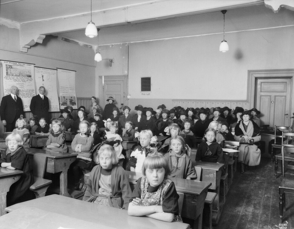 En jenteklasse på Møllergata skole med mødrene sittende i bakgrunnen ca. 1925. En jenteklasse på Møllergata skole med mødrene sittende i bakgrunnen ca. 1925.