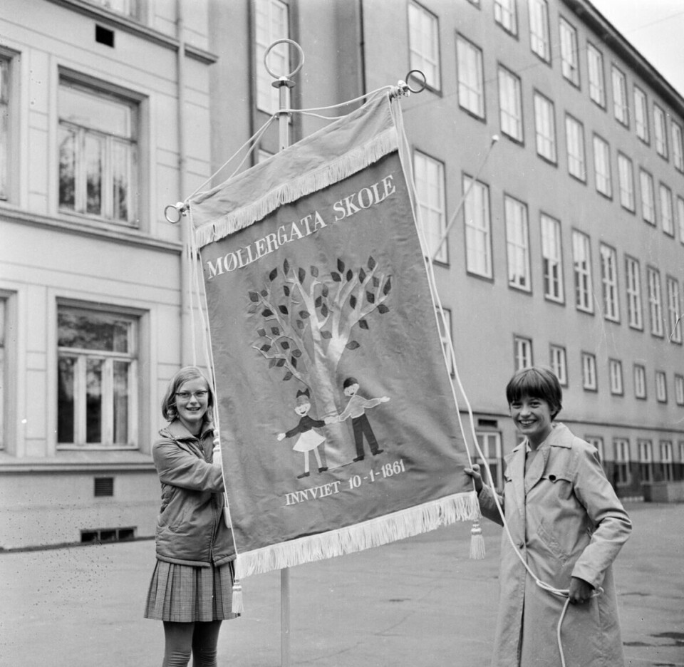 Solveig Sigstad og Merete Armand viser stolt farm Møllergata skoles nye fane i mai 1968. Skolekorpset er landets eldste.(Arbeiderbladet/Arbeiderbevegelsens arkiv og bibliotek /Arbeiderbevegelsens arkiv og bib) Solveig Sigstad og Merete Armand viser stolt farm Møllergata skoles nye fane i mai 1968. Skolekorpset er landets eldste.