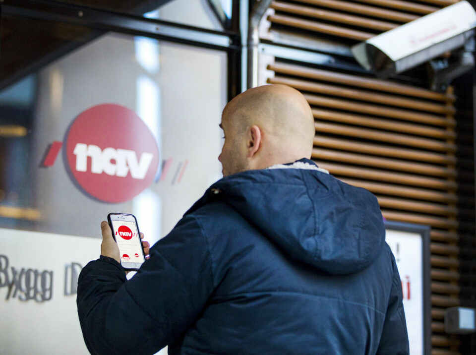 Digitaliseringen gjør livet enklere for mange, men slik systemene er laget i dag utgjør de murer snarere enn broer inn i arbeidslivet, skriver Ingrid Rosendorf Joys. Mann utenfor Nav-kontor med mobiltelefon. App, digitalisering, arbeidsledighet, innvandring. (Illustrasjonsfoto)