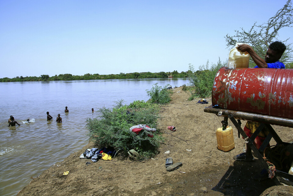 Folk svømmer i Nilen mens en annen fyller opp en vannbeholder som følge av vannstans i Khartoum, hovedstaden i Sudan. Folk svømmer i Nilen mens en annen fyller opp en vannbeholder som følge av vannstans i Khartoum, hovedstaden i Sudan. Foto: AP / NTB