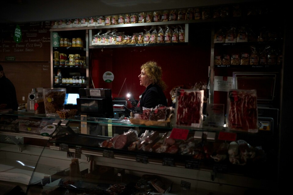 En selger bruker mobillyset for å finne frem varer i en matbutikk i Barcelona.(Emilio Morenatti/AP) En selger bruker mobillyset for å finne frem varer i en matbutikk i Barcelona.