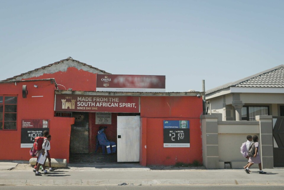 Sør-afrikanske elever går forbi en pub med tydelig alkoholreklame på vei til og fra skolen. Det er denne typen markedsføring FORUT vil at Oljefondet skal slå hardt ned på.(Moses Tau) Sør-afrikanske skolebarn går forbi en pub med tydelig alkoholreklame på vei til og fra skolen.
