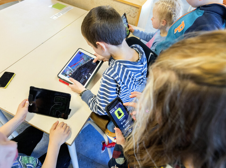 Illustrasjonsfoto. Bildet viser barn som holder på med mobiler og ipader i et klasserom.