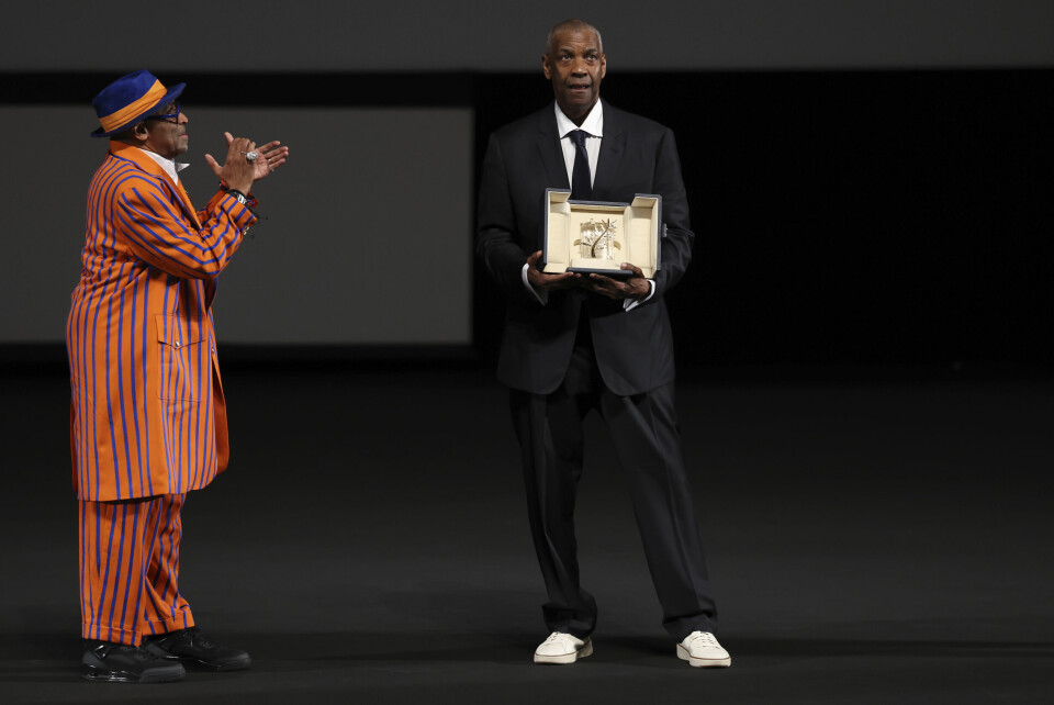 Spike Lee, fullt utstyrt i fargene til favorittlaget New York Knicks, ser på mens kompisen Denzel Washington hedres med en Æres-Gullpalme under filmfestivalen i Cannes. Spike Lee, fullt utstyrt i fargene til favorittlaget New York Knicks, ser på mens kompisen Denzel Washington hedres med en Æres-Gullpalme under filmfestivalen i Cannes. Foto: Sameer Al-Doumy / Pool via AP / NTB