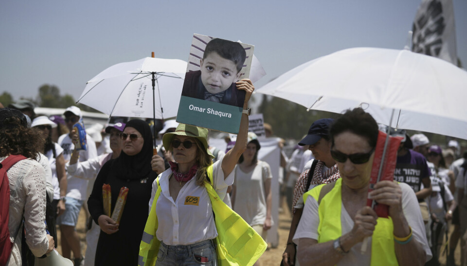 Israelske fredsaktivister, den ene med et bilde av et barn som er drept i Gaza, demonstrerer med krav om slutt på Israels krig og løslatelse av gislene i Gaza.