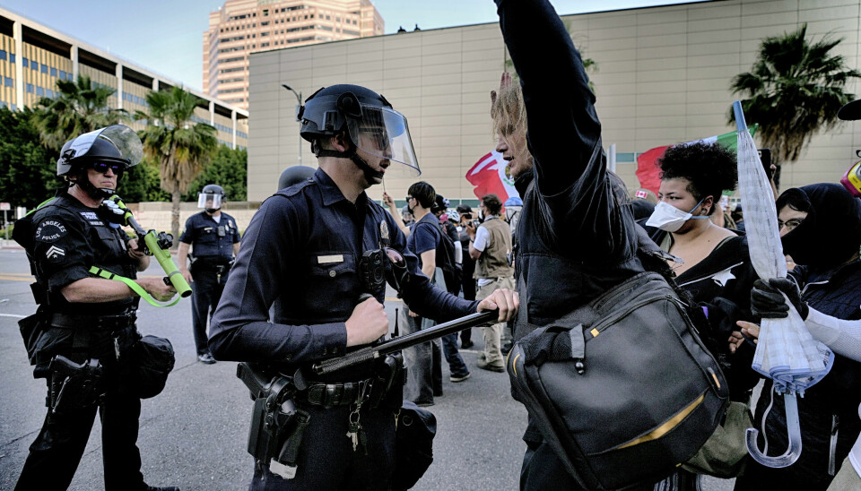 En politimann i Los Angeles dytter tilbake en demonstrant på en gate nær en føderal bygning i sentrum av storbyen.