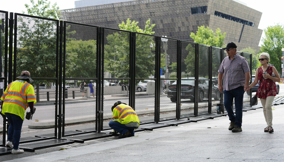 Et par går forbi mens gjerder settes opp i Washington i forkant av militærparaden.