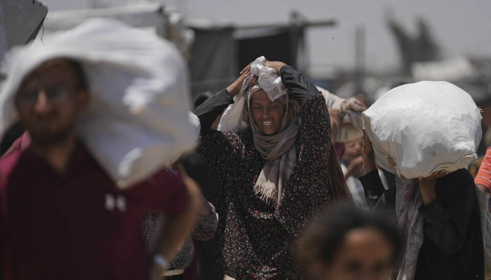 Palestinere bærer sekker med nødhjelp etter å ha oppsøkt en matsentral som drives av USA-støttede Gaza Humanitarian Foundation i Rafah. Bildet ble tatt mandag.