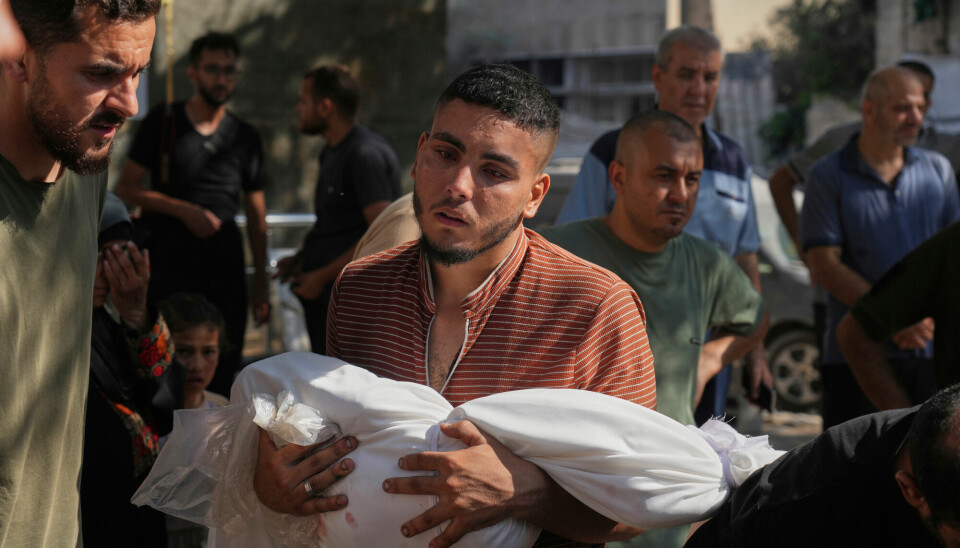 En mann bærer et dødt barn utenfor Shifa-sykehuset etter dødelige angrep i Gaza mandag hvor minst 67 er døde.