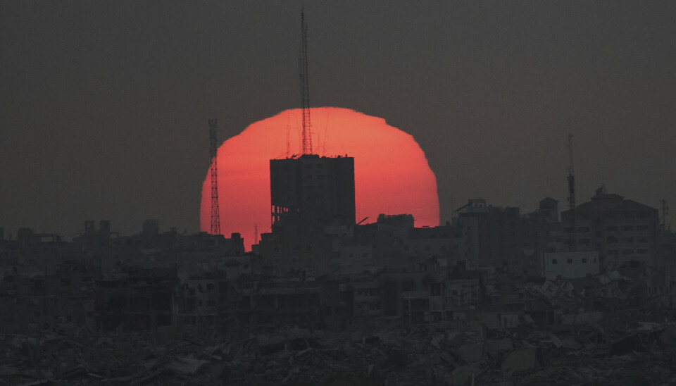 Solen går ned over ødelagte bygninger på Gazastripen, sett fra det sørlige Israel, tirsdag.