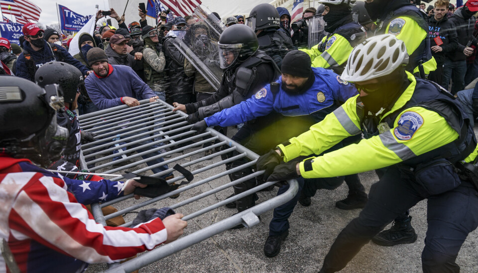 Demonstranter forsøker å bryte seg gjennom gjerdene foran Kongressen 6. januar 2021.